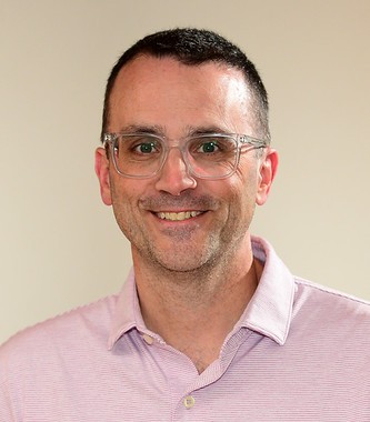 A demure yet sophisticated headshot of Bryan McGrath, GCC's Secretary, with a blurred yet sophisticated background
